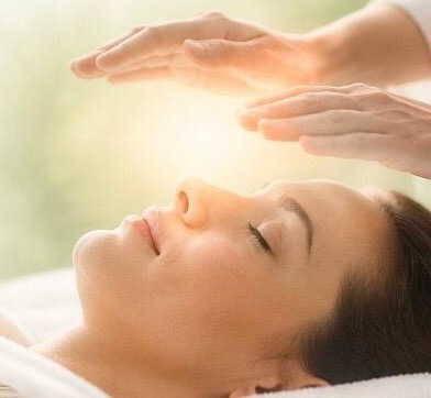 Reiki practitioner's hands held just above a relaxed client's face